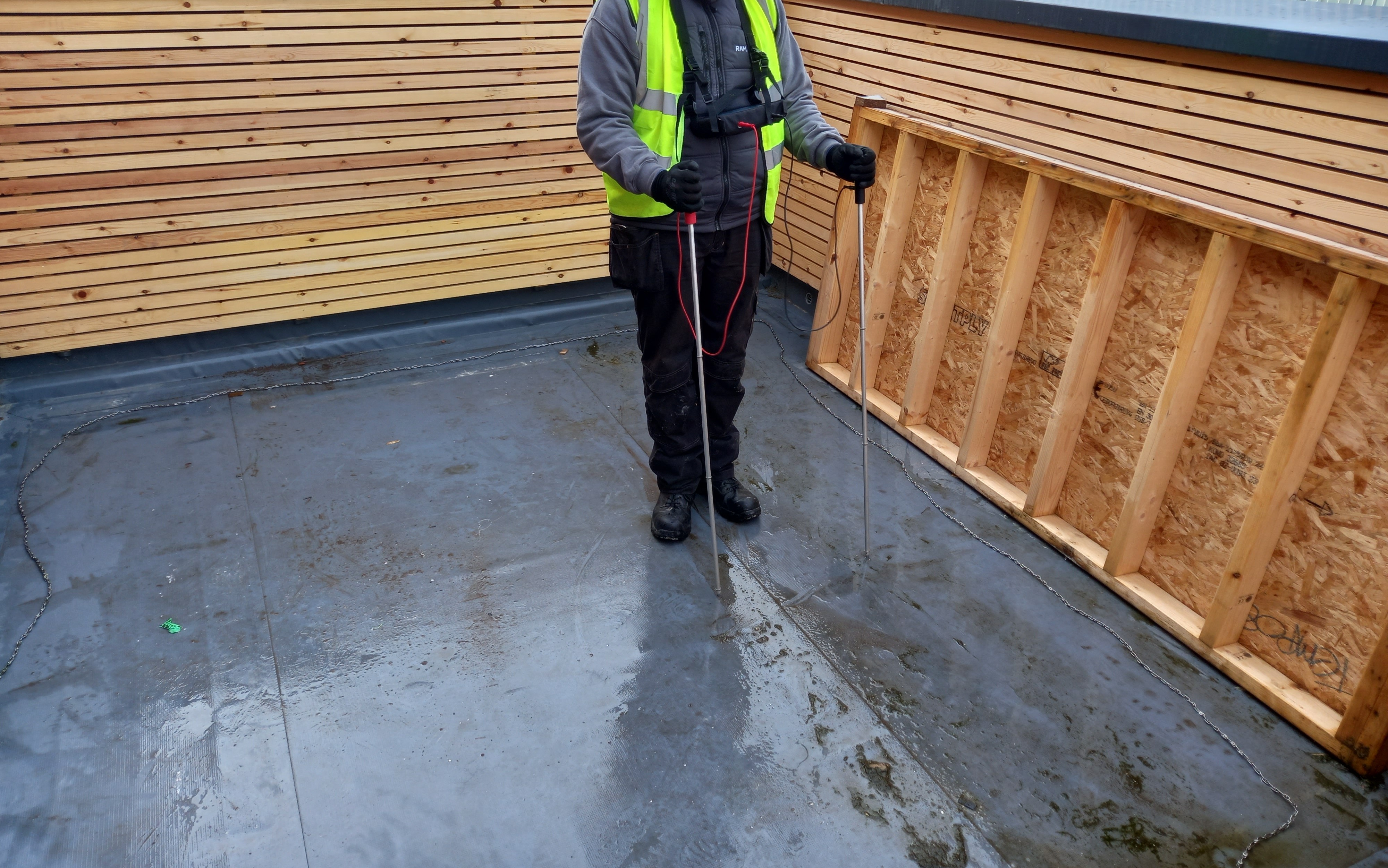 A Ram Building Consultancy technician conducting a Dynamic Leak Investigation on a flat roof using electronic leak detection probes.