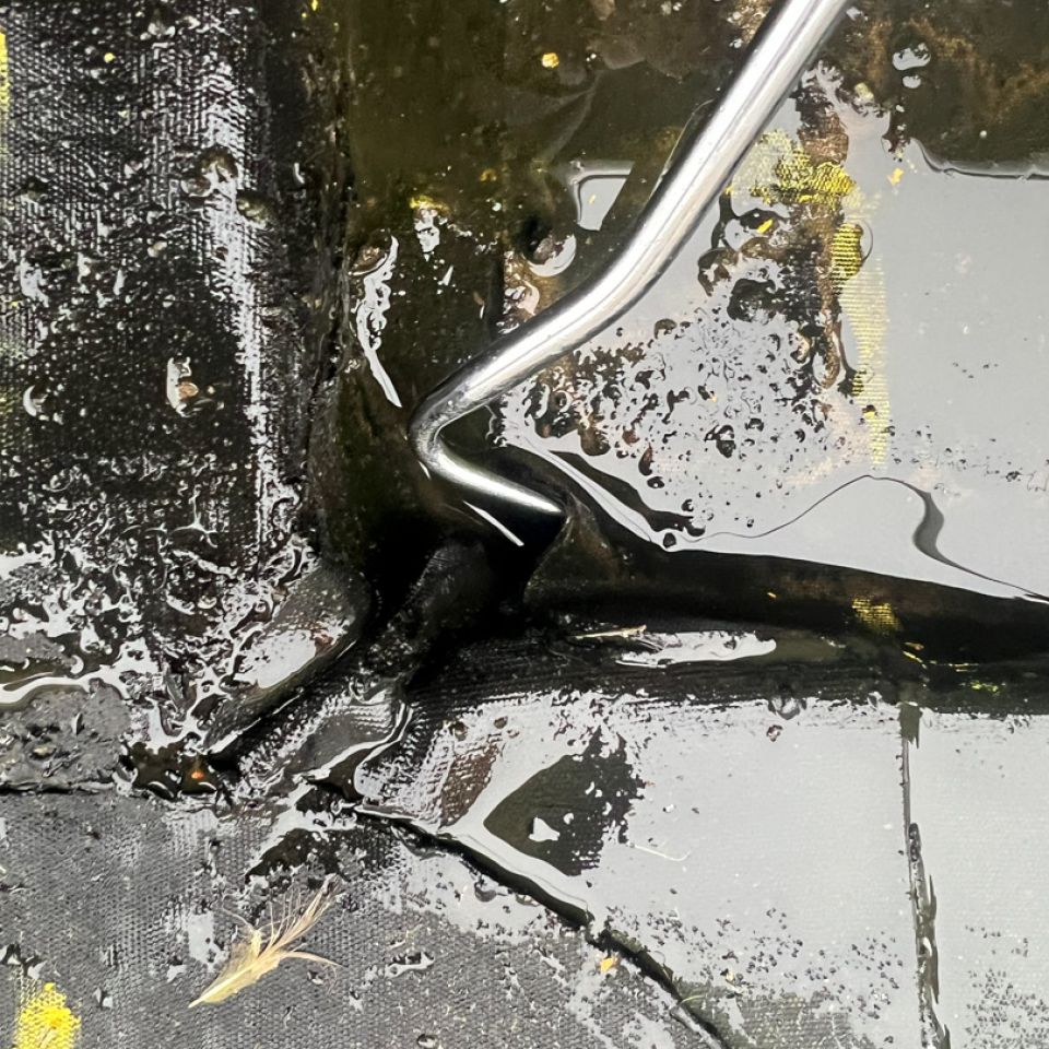Close-up of liquid bitumen seeping through a cracked flat roof membrane joint during a Ram Building Consultancy leak investigation.